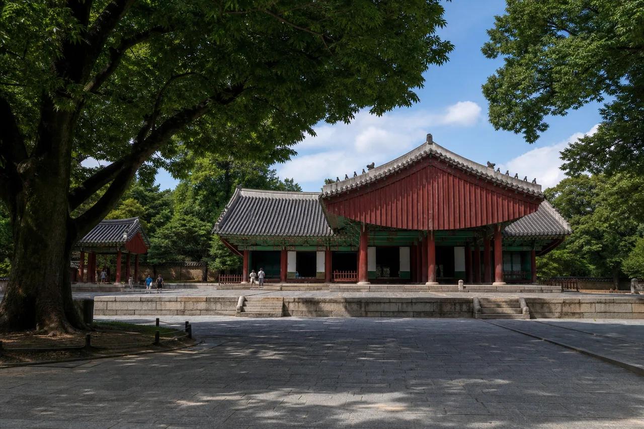 큰 나무 그늘과 돌마당 뒤로 전통 전각이 보이는 전주 경기전