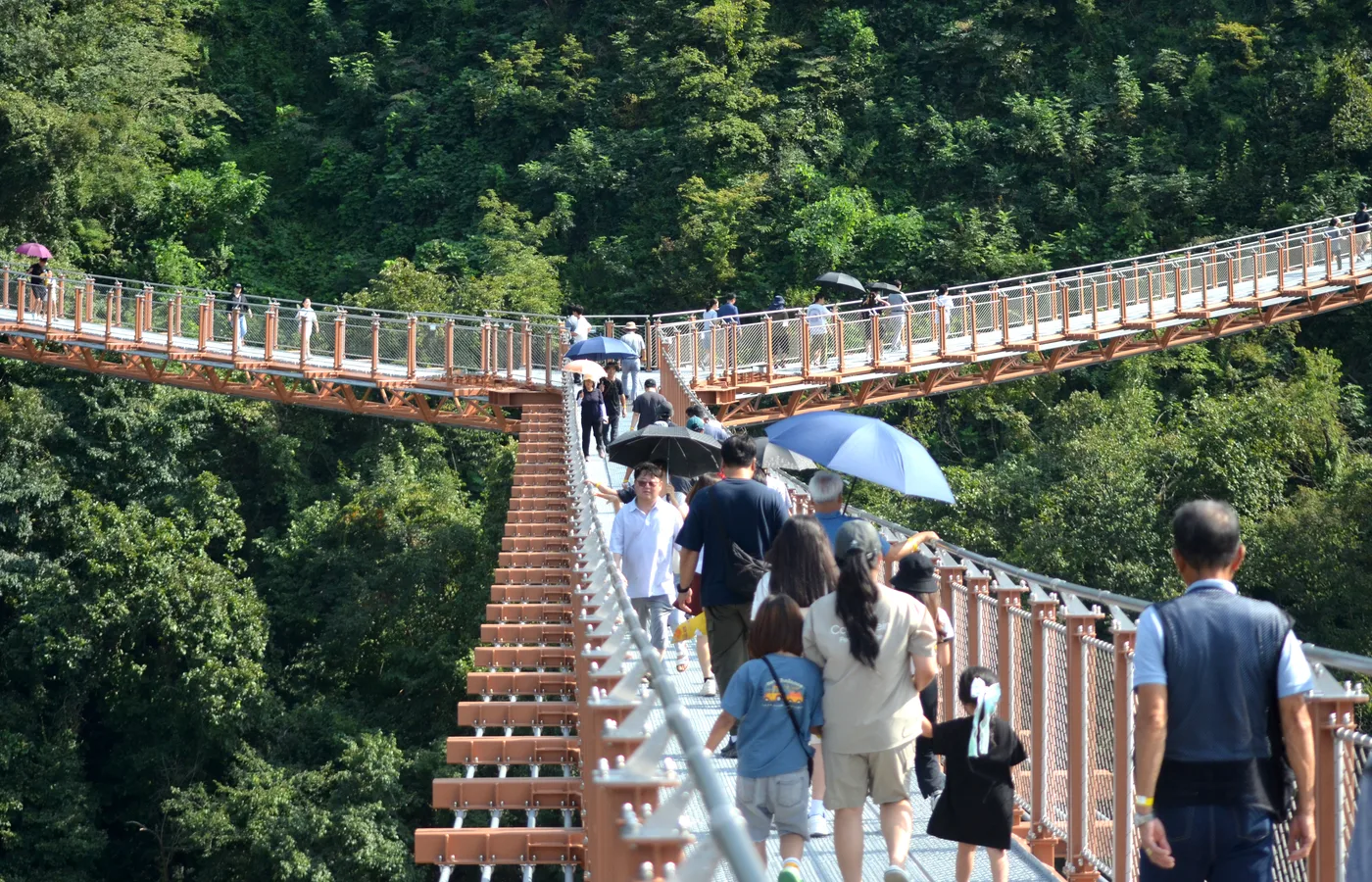 우산을 든 방문객이 계단을 올라 한탄강 출렁다리로 향하는 모습