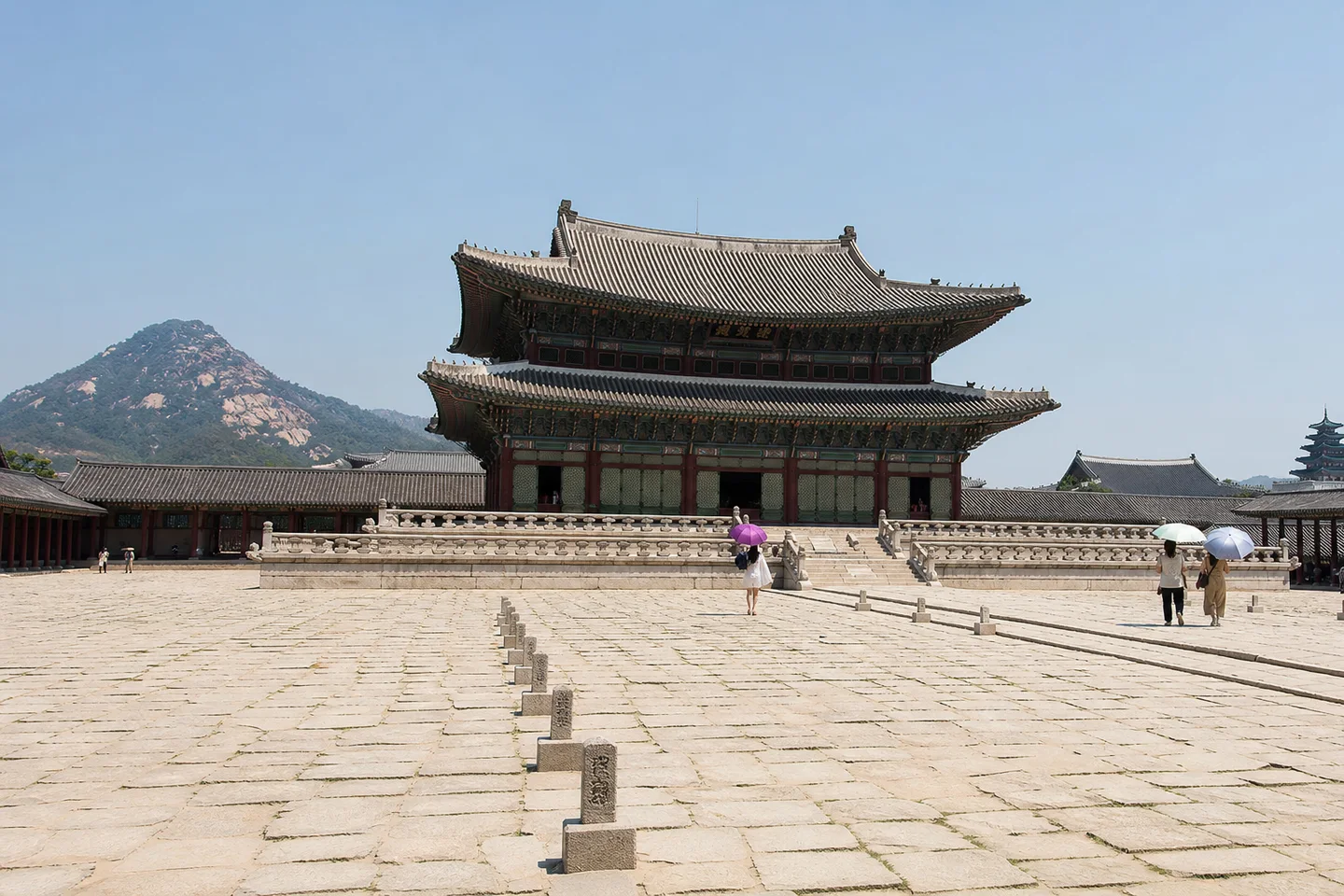 여름 아침 경복궁 근정전과 넓은 돌마당을 걷는 방문객