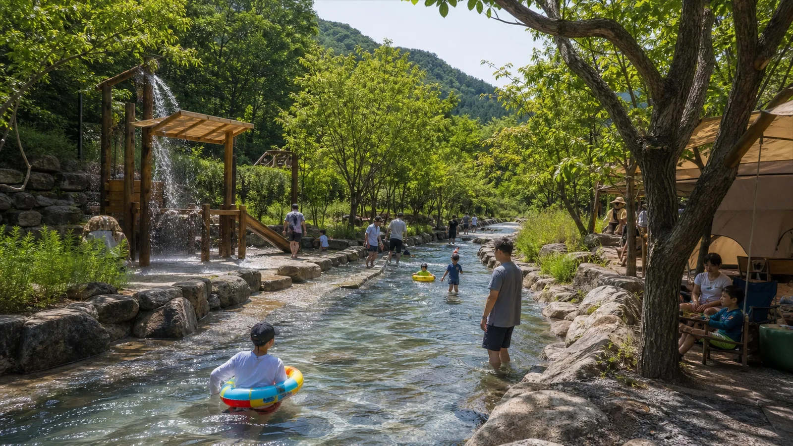 숲 아래 캠프닉 텐트 옆으로 길게 이어지는 가족 물놀이 수로