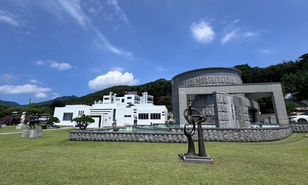 잔디 조각공원과 흰 건물이 있는 휘목아트리조트 전경